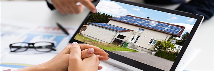 twee mensen die kijken naar een laptop met een huis met zonnepanelen