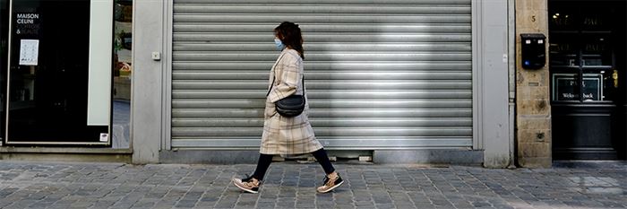 Vrouw met hoofddoek loopt voor een gesloten winkelpand