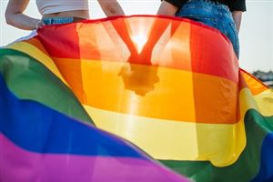 Pride vlag met twee mensen die elkaars hand vasthouden