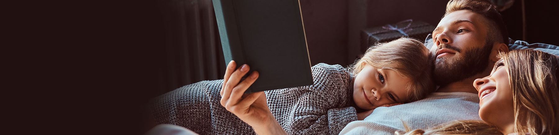 Vader ligt met twee kinderen op de bank een boek te lezen
