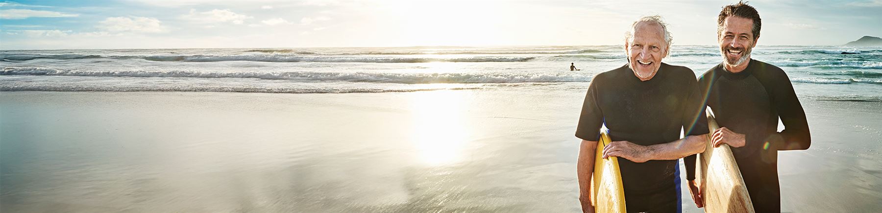 vader en zoon die met hun surfboad de zee uit komen lopen