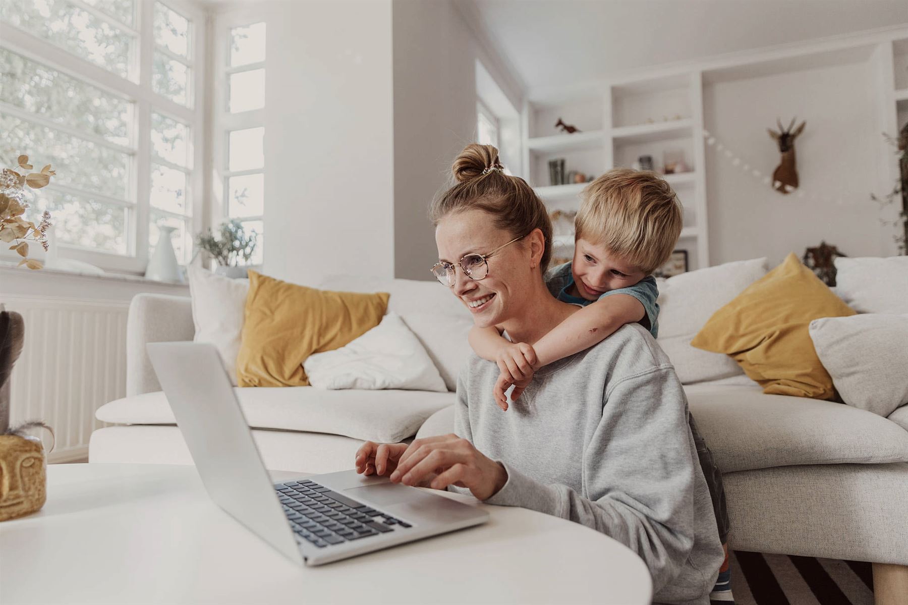 Vrouw zit thuis achter de laptop met kind 