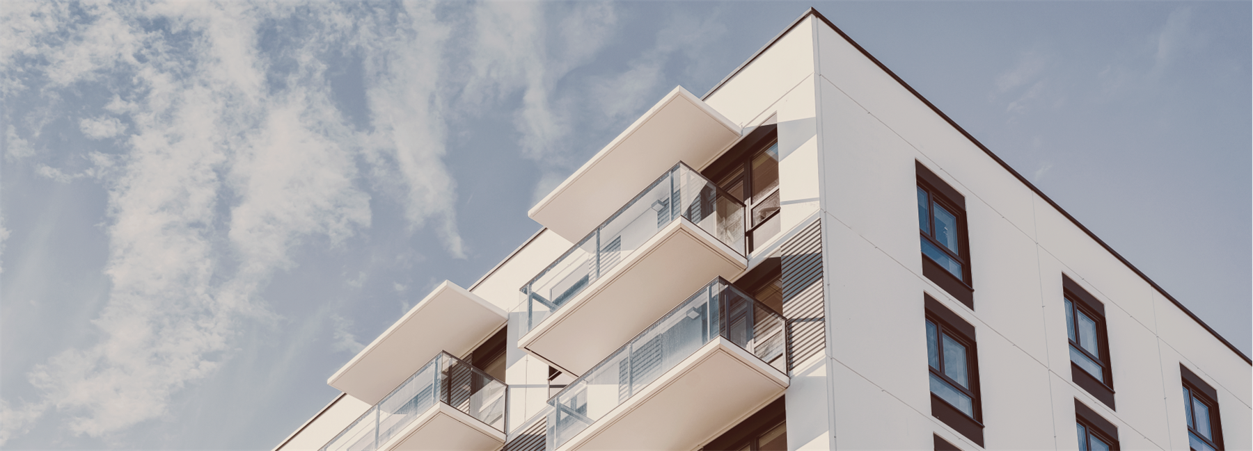 Een wit appartementencomplex met een blauwe lucht