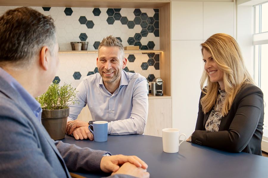 advieseur zit om de tafel met 2 klanten